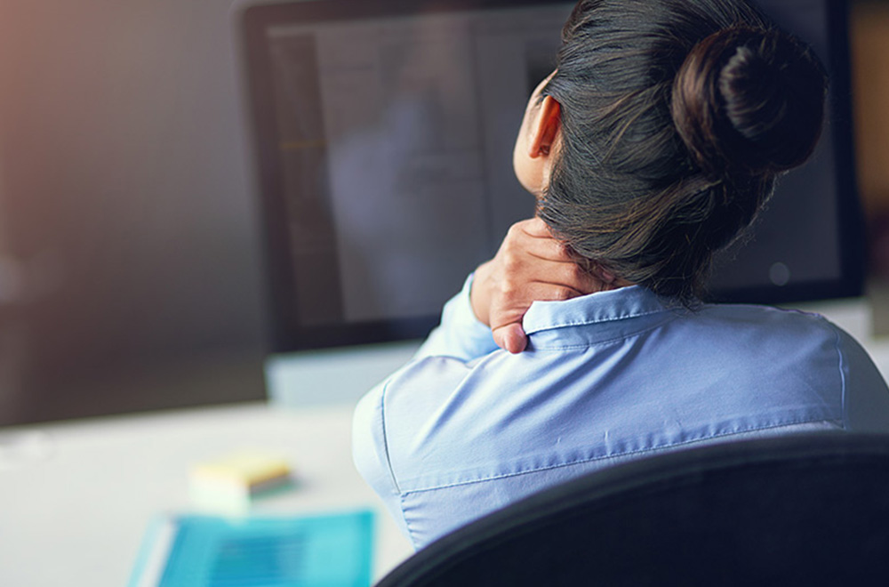 Office worker experiencing neck and shoulder tightness at a computer Office worker experiencing neck and shoulder tightness at a computer