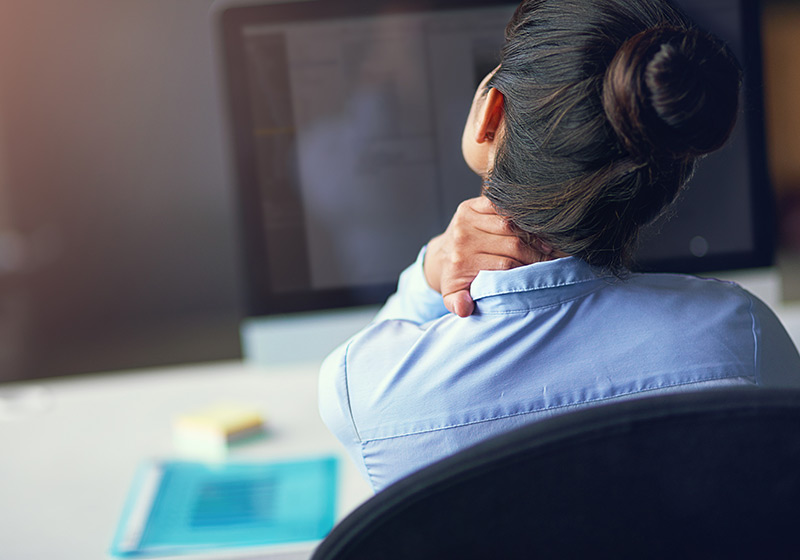 Office worker experiencing neck and shoulder tightness at a computer Office worker experiencing neck and shoulder tightness at a computer